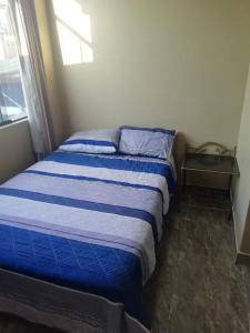 a bed with a blue comforter in a bedroom at Apart Hotel Costa Verde in Tacna