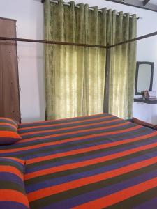 a bedroom with a bed with a striped blanket at Savenndra Resorts in Malwana