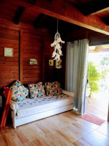 1 dormitorio con cama con almohadas y lámpara de araña en Chalés praia do Rosa SC piscina comp, en Imbituba