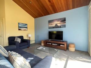ein Wohnzimmer mit einem Sofa und einem Flachbild-TV in der Unterkunft Beachy Haven at Sails close to the Beach in Inverloch