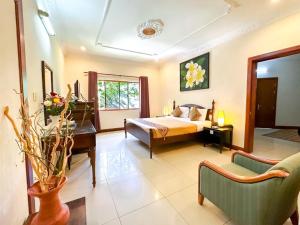 Maison Arnica Hotel & Restaurant في بنوم بنه: غرفة نوم بسرير وطاولة وكراسي