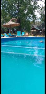 a blue swimming pool with chairs and an umbrella at Cabaña Alamos Altos in Belén de Escobar