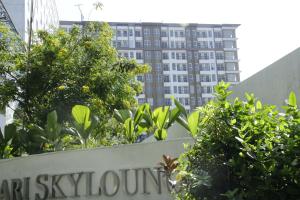 um sinal em frente a um edifício com árvores em Apartemen Skylounge Makassar em Makassar