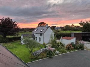 a white house in a yard with a sunset at Lehane's Cottage in Macroom