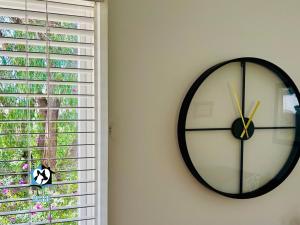 a black and white clock on a wall next to a window at 3BR Updated Coastal Beach House in Funky Port Elliot in Port Elliot