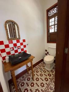 a bathroom with a toilet and a table with a mirror at Casa Blanca María Barranquilla - Authentic colonial house in Barranquilla