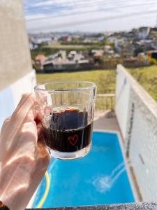 a person holding a drink in a cup on a balcony at casa de temporada Gabyviti in Sao Paulo
