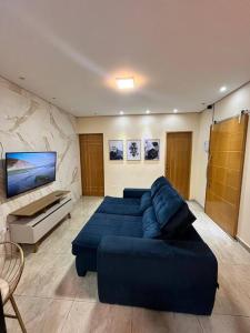 a living room with a blue couch and a tv at casa de temporada Gabyviti in Sao Paulo