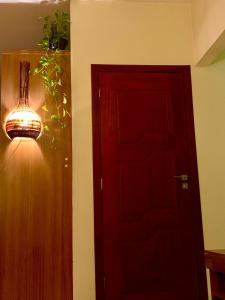 a red door with a light and a plant next to it at Hostel Portal da Montanha in Blumenau