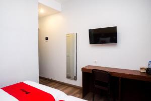 a bedroom with a desk and a television on the wall at RedDoorz near Tentrem Mall Semarang in Semarang