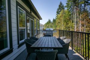 a wooden table on a deck with chairs on a house at Luxurious Home in Lake Cowichan in Lake Cowichan