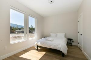 a white bedroom with a bed and a large window at Luxurious Home in Lake Cowichan in Lake Cowichan