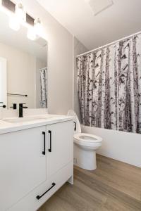 a white bathroom with a toilet and a shower curtain at Luxurious Home in Lake Cowichan in Lake Cowichan