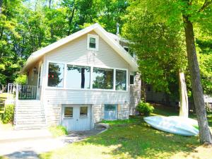 a small house with a boat in front of it at Cavalier Cottage - Private Lakefront w Kayaks! in Honor