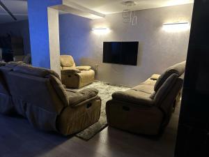 uma sala de estar com 2 cadeiras e uma televisão de ecrã plano em Trio villa with falls in compound فلا بحديقة كبيره وشلالات صناعية em Sheikh Zayed
