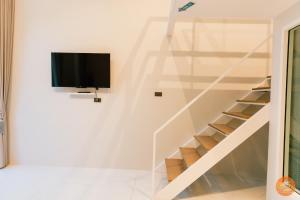 a staircase with a tv in a white wall at Miami Seaview in Ban Pak Ba Ra