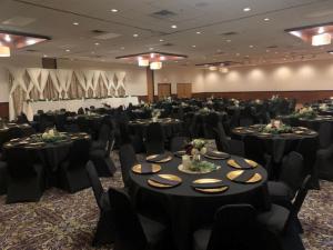 une salle de banquet avec des tables et des chaises noires dans l'établissement Brookings Inn, à Brookings