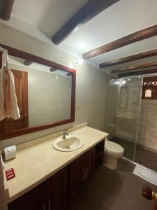 a bathroom with a sink and a toilet and a mirror at Muisca Hotel Villa de Leyva in Villa de Leyva