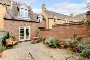 a brick wall with a patio in front of a house at Gem Cottage in Chipping Campden