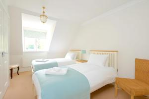 a bedroom with two beds and a chair at Gem Cottage in Chipping Campden