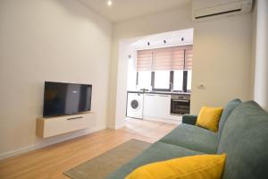 uma sala de estar com um sofá azul e uma televisão em Tirana Central Apartments em Tirana