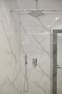 W białej łazience z przeszklonymi drzwiami znajduje się prysznic. w obiekcie Tirana Central Apartments w Tiranie