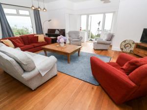 a living room with red couches and a table at Penmarth House in Helston