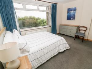 a bedroom with a bed and a window and a chair at Penmarth House in Helston