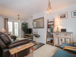 a living room with a leather couch and a tv at Pebbles Foxglove Way in Bridport