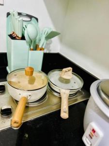 a counter top with two pans and wooden spoons at Simple but cozy 1BR Shore 2 MOA in Manila