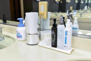 a bathroom counter with bottles of cleaning products on a sink at Hotel Palms Tenmonkan in Kagoshima