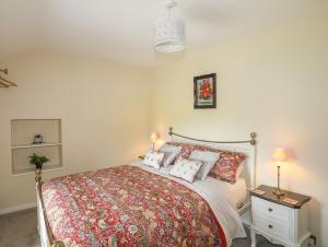 ein Schlafzimmer mit einem Bett und einem Tisch mit Lampen in der Unterkunft Frongoch Cottage in Pentraeth