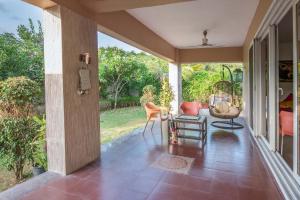 an open porch with chairs and a door to a garden at Serene Villa by StayVista - A Hill-View Villa with Plunge pool in Karjat