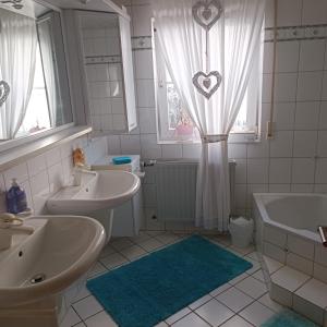 un bagno con due lavandini, una vasca e una finestra di Ferienwohnung Gogelhopf EG a Unterschneidheim