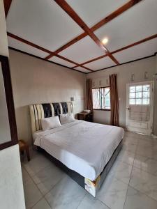 een slaapkamer met een groot wit bed in een kamer bij RON'S Guest House Berastagi Backpacker Rooms in Berastagi