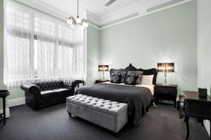 WaratahにあるBischoff Hotelのベッドルーム1室(ベッド1台、椅子、ソファ付)