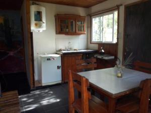 uma cozinha com uma mesa e um frigorífico branco em AlfaCabañas em San Marcos Sierras