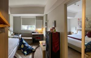 a hotel room with two beds and a desk and a kitchen at Grand Cordela Hotel Bandung in Bandung