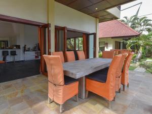 een eetkamer met een tafel en oranje stoelen bij Villa Singkenken in Kubutambahan