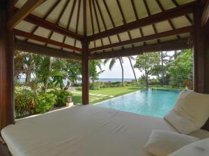 a room with a bed and a swimming pool at Villa Singkenken in Kubutambahan