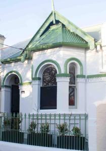 uma casa branca com um telhado verde e uma cerca em Churchill’s Rest em Sydney