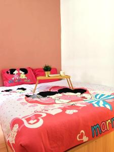 Una cama con un edredón rojo con una mesa. en GWarmStay@GoldenHillsNightMarket, en Brinchang