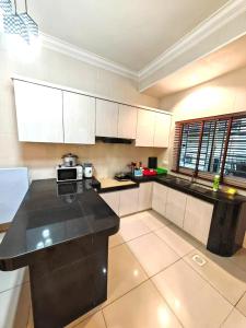 a kitchen with white cabinets and a black counter top at GWarmStay@GoldenHillsNightMarket in Brinchang