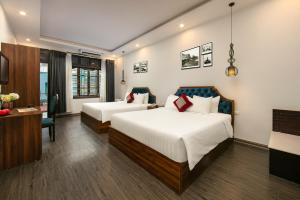a hotel room with two beds and a desk at La Renta Premier Hotel & Spa Hanoi in Hanoi