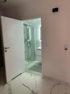 a white bathroom with a shower and a glass door at Apart 89A Angielska Grobla 5 - Gdańsk Śródmieście in Gdańsk