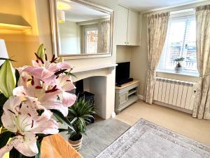 a living room with a fireplace and pink flowers at 1 Aplands in Blandford Forum