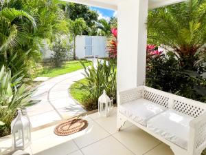 a white bench on a porch with palm trees at Villa White Horizon by Sealodge in Pointe aux Canonniers