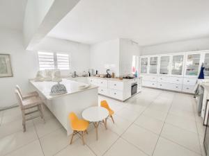 a white kitchen with white cabinets and orange chairs at Villa White Horizon by Sealodge in Pointe aux Cannoniers