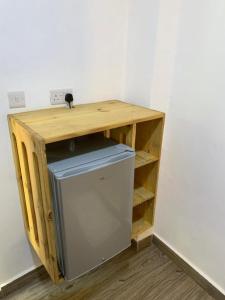 einen kleinen Holzschreibtisch mit einem Kühlschrank in einem Zimmer in der Unterkunft Panopano House in Nungwi
