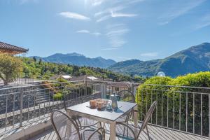 een tafel en stoelen op een balkon met uitzicht op de bergen bij Villa Tremezzo in Tremezzo